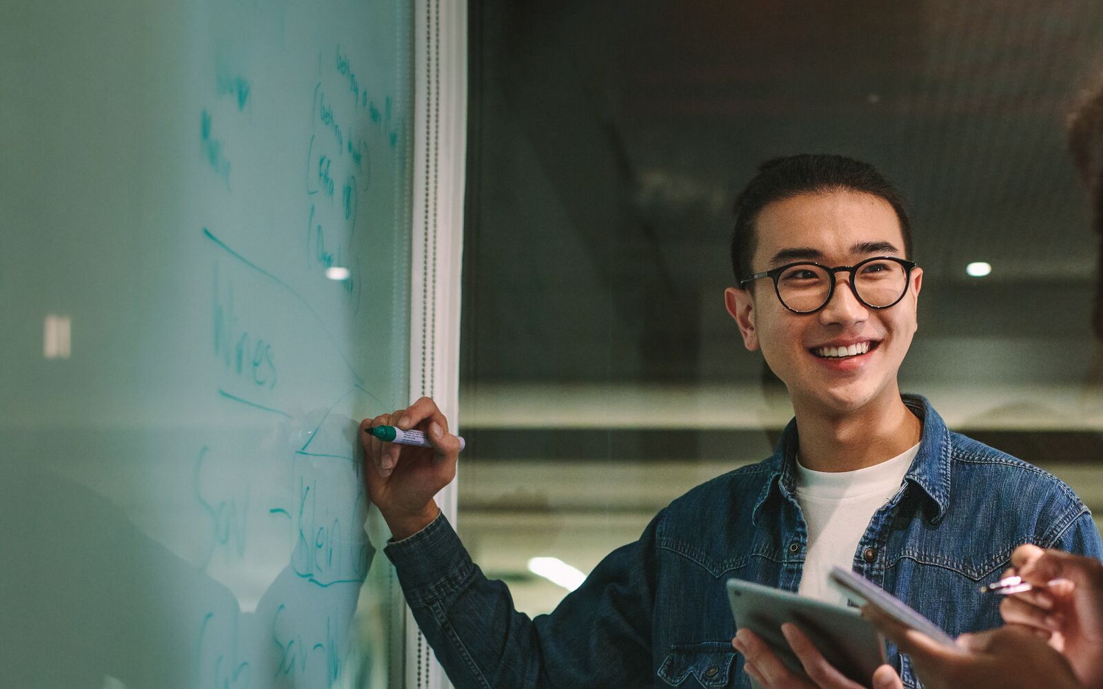 Student writing on glass board in classroom. Male student writing on board during group study in class.; Shutterstock ID 1253455588; purchase_order: Main Visual; job: ; client: ; other: